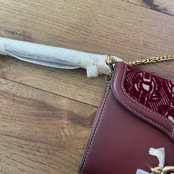 Coach embroidered Elegant Burgundy Clutch with Gold Accent.